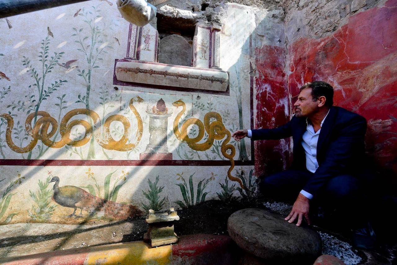 Man squatting next to a shrine in the ruins of Pompeii, Italy