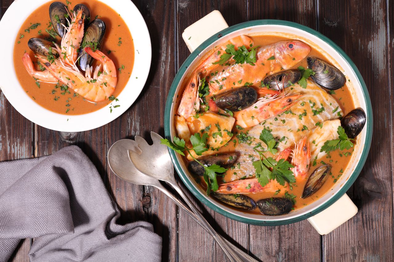 Bowl and pot of boullabaise garnished with parsley